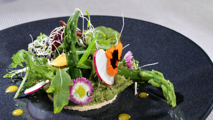 La fraîcheur printanière d'une fine tarte au parmesan tartinée au pesto asperges vertes du pays, raids, jeunes pousses